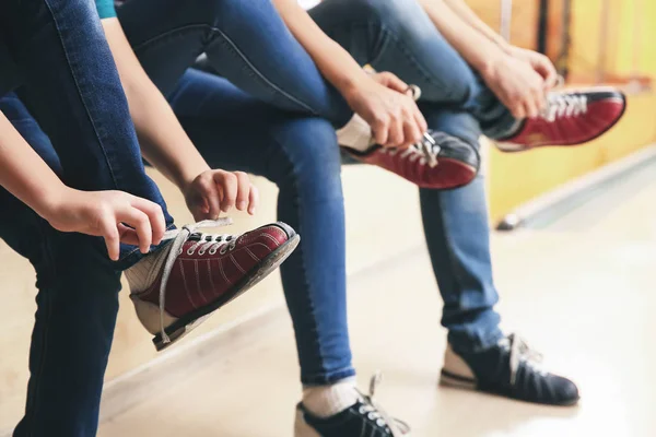 Family changing shoes before playing bowling in club