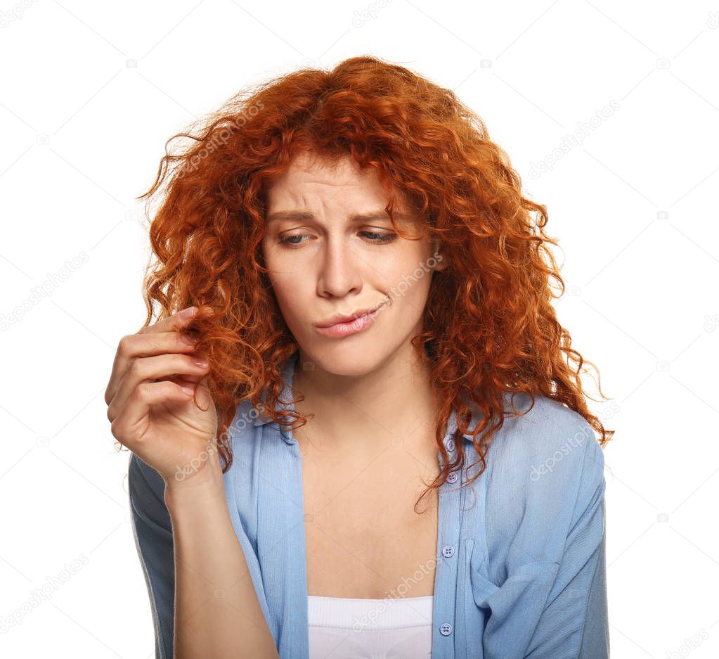 Beautiful woman displeased with her hair on white background