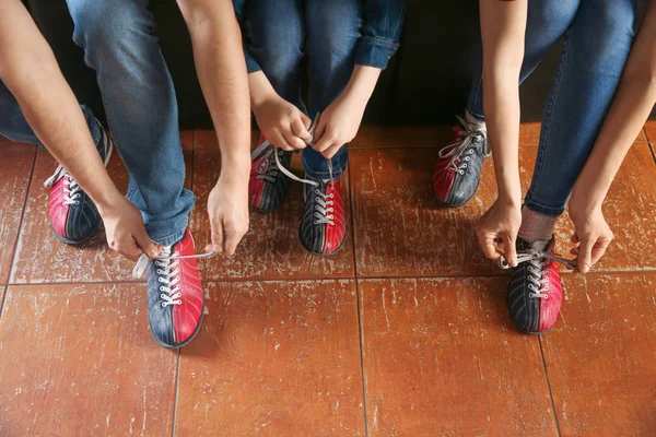 Family changing shoes before playing bowling in club