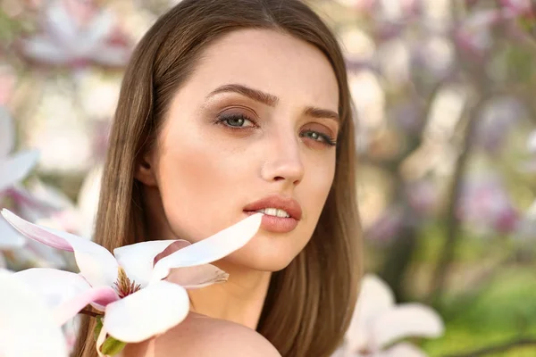 Portrait of beautiful young woman near blooming magnolia tree outdoors — Stock Photo, Image