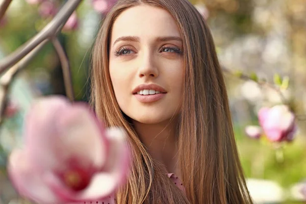 Retrato de una hermosa mujer joven cerca del árbol de magnolia floreciente al aire libre — Foto de Stock