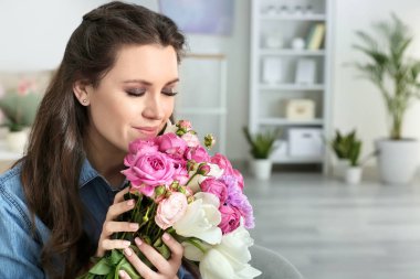 Evinde bir buket çiçekle güzel genç bir kadın.