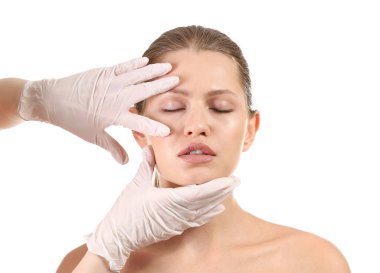 Plastik cerrah beyaz arka plan üzerinde genç kadının yüzüne dokunmadan