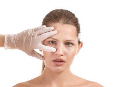 Plastik cerrah beyaz arka plan üzerinde genç kadının yüzüne dokunmadan