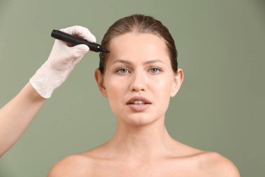 Plastik cerrah renk arka plan karşı kadın yüzüne işaretleme uygulayarak