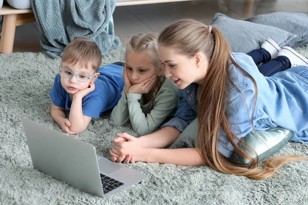 Молода мати з маленькими дітьми дивиться мультфільми вдома — стокове фото