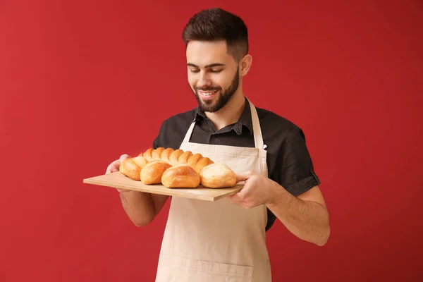 Panadero con pan fresco sobre fondo de color — Foto de Stock