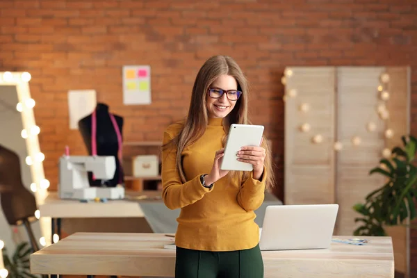 Beautiful female business owner working with tablet PC in atelier — Stock Photo, Image