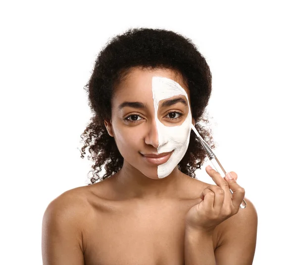 Ung afro-amerikansk kvinna applicera mask på hennes ansikte mot vit bakgrund — Stockfoto
