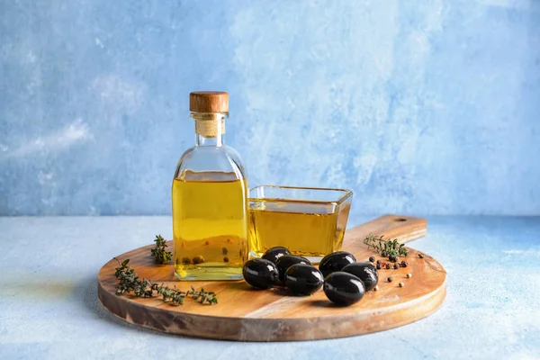 Tablero de madera con sabroso aceite de oliva sobre fondo de color — Foto de Stock