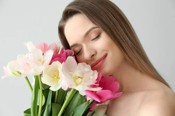 Young woman with bouquet of beautiful tulips on light background — Stock Photo, Image