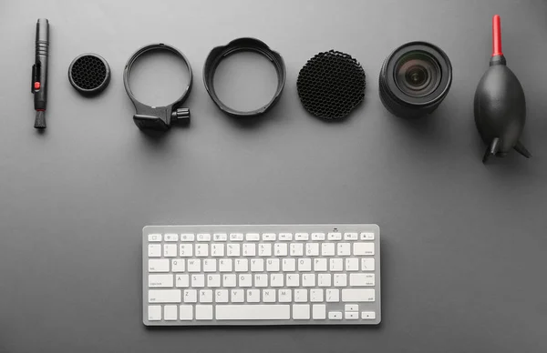 Equipamento moderno de fotógrafo profissional e teclado de computador em fundo cinza — Fotografia de Stock