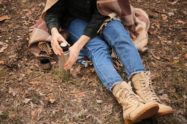 Mujer con termo descansando en el bosque — Foto de Stock