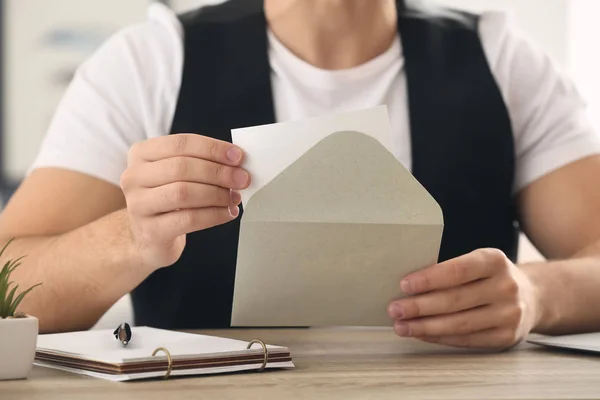 Young man opening envelope with invitation at home, closeup — Stock Photo, Image