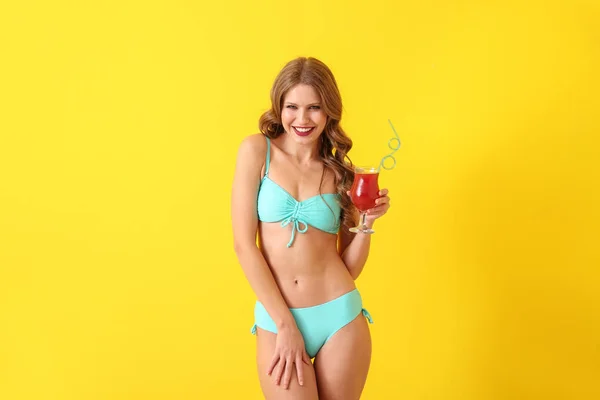 Hermosa mujer joven en traje de baño y con cóctel en el fondo de color — Foto de Stock