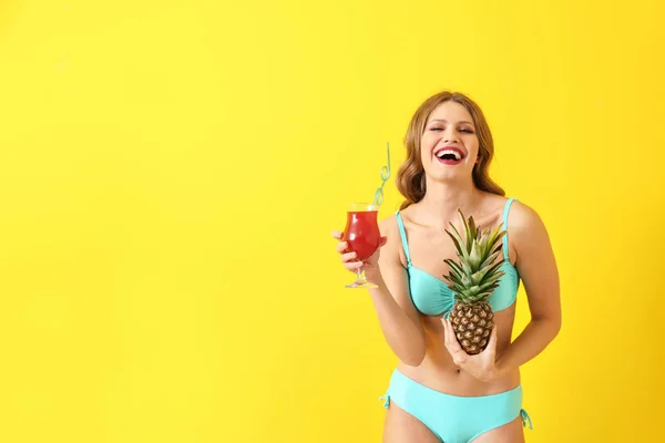 Schöne junge Frau im Badeanzug, mit Ananas und Cocktail auf farbigem Hintergrund — Stockfoto