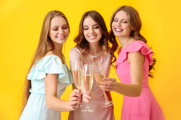 Piękne młode kobiety piją szampana na kolorowym tle — Zdjęcie stockowe