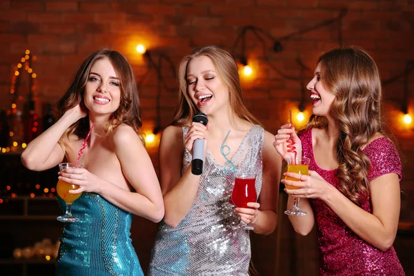 Hermosas mujeres jóvenes con cócteles y micrófono en la fiesta —  Fotos de Stock