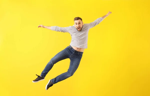Jumping young man on color background — Stock Photo, Image