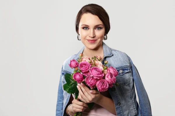 Beautiful young woman with bouquet of flowers on light background — Stock Photo, Image