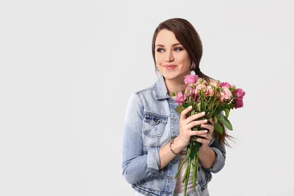 Belle jeune femme avec bouquet de fleurs sur fond clair — Photo