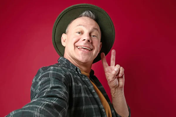 Happy middle-aged man taking selfie on color background — Stock Photo, Image