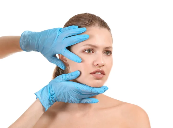 Пластичний хірург торкається обличчя молодої жінки на білому тлі — стокове фото