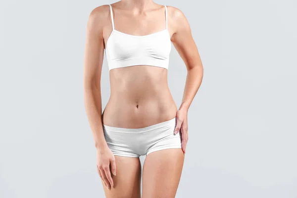 Mooie jonge vrouw in ondergoed op lichte achtergrond. Plastisch chirurgie concept — Stockfoto