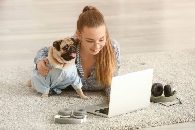 Evde sevimli pug köpek ve dizüstü bilgisayar ile Genç kız