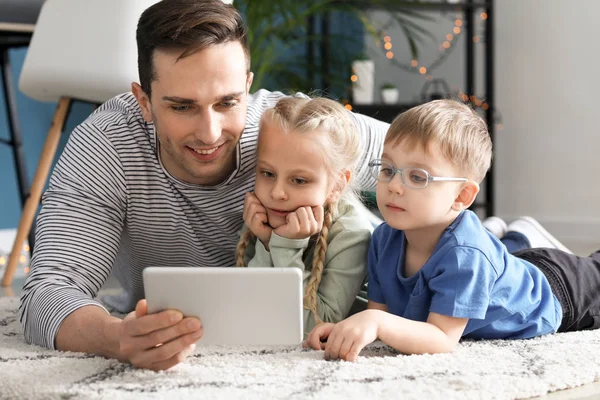 Молодий батько з маленькими дітьми дивиться мультфільми вдома — стокове фото