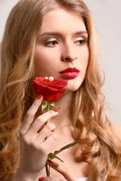 Hermosa mujer joven con maquillaje brillante y flor sobre fondo claro —  Fotos de Stock