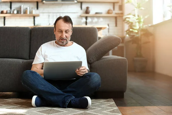 Bello uomo maturo che utilizza il computer portatile a casa — Foto Stock