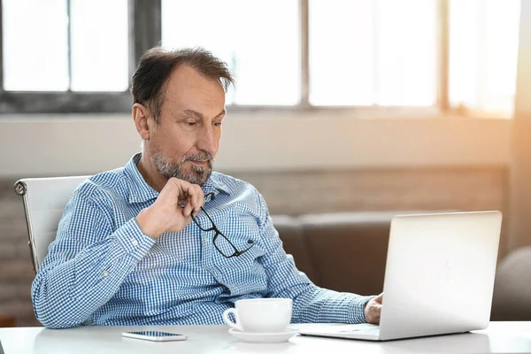 Knappe volwassen man met laptop thuis — Stockfoto