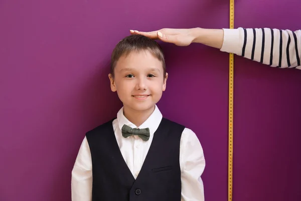 Mother measuring height of her son near wall — Stock Photo, Image
