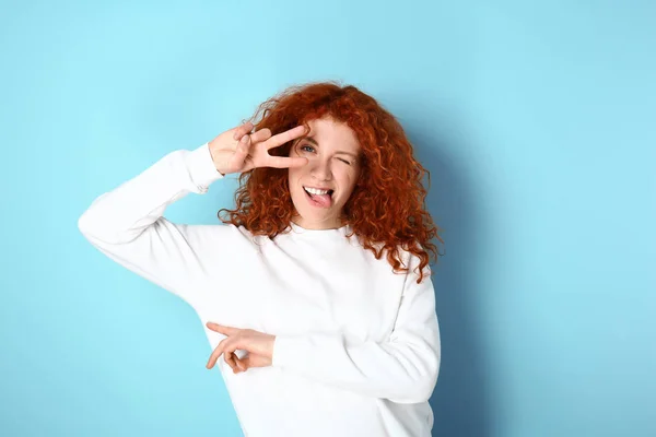 Beautiful redhead woman showing victory gesture on color background — 스톡 사진