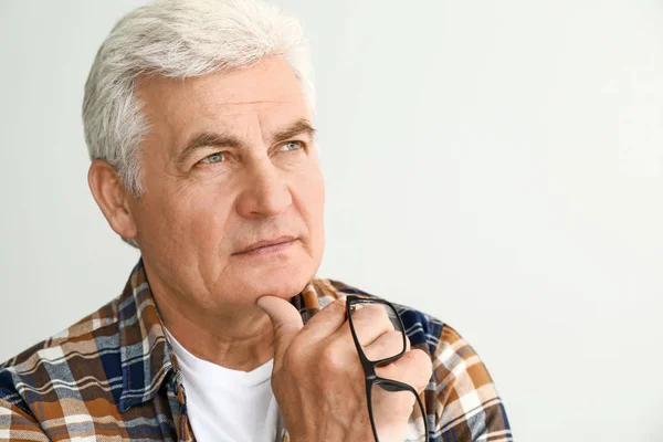 Portrait of thoughtful senior man on light background — Stock Photo, Image