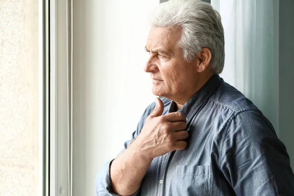 Portrait of handsome senior man near window at home — Stock Photo, Image