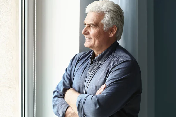 Portrait of handsome senior man near window at home — Stock Photo, Image