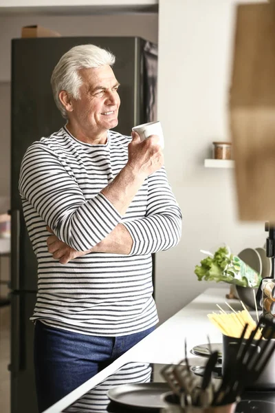 Portrait of handsome senior man drinking coffee in kitchen at home — Stock Photo, Image