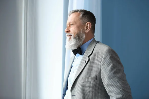 Portrait of handsome senior man near window at home — Stock Photo, Image