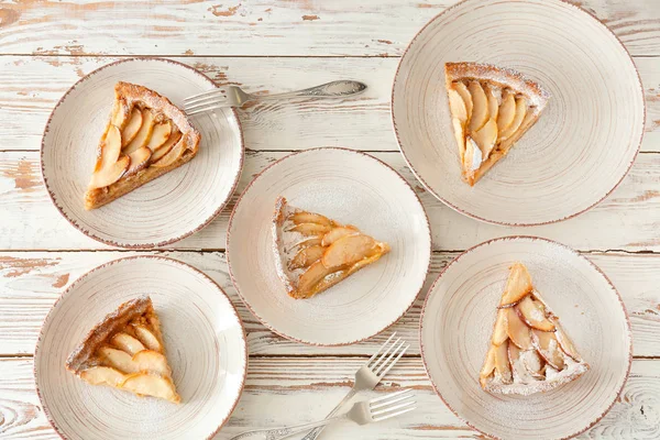 Assiettes avec tarte aux pommes savoureuse sur fond blanc en bois — Photo