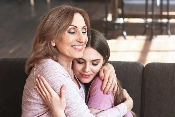 Feliz madre e hija sentadas en el sofá en casa —  Fotos de Stock