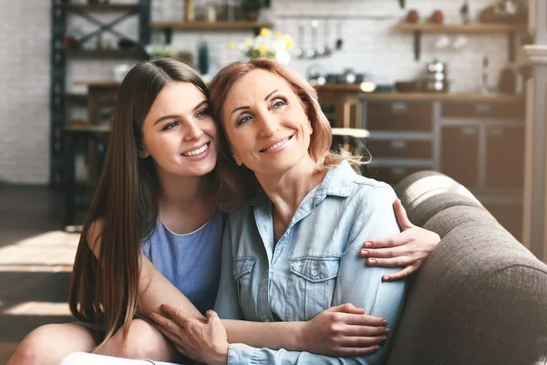 Feliz madre e hija sentadas en el sofá en casa —  Fotos de Stock