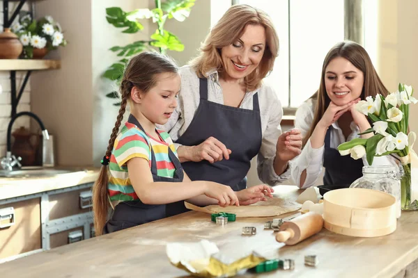 Klein meisje met haar moeder en grootmoeder koken koekjes in de keuken thuis — Stockfoto