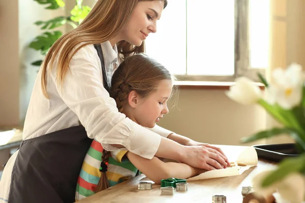 Klein meisje met haar moeder koken koekjes in de keuken thuis — Stockfoto