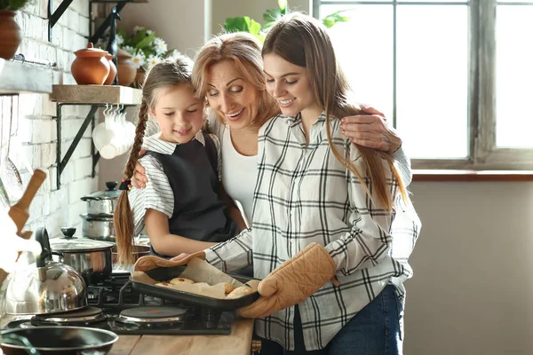 Klein meisje met haar moeder en grootmoeder koken koekjes in de keuken thuis — Stockfoto