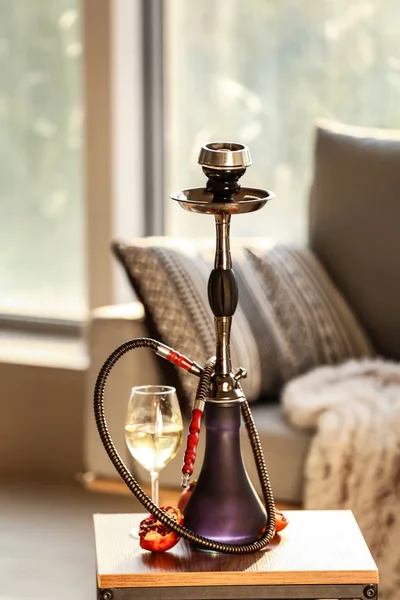 Hookah, granada y vaso de alcohol en la mesa en la habitación — Foto de Stock