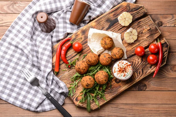 Board with tasty falafel balls and sauce on wooden table — Stock Photo, Image