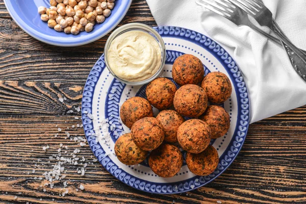 Placa con sabrosas bolas de falafel y salsa sobre mesa de madera —  Fotos de Stock