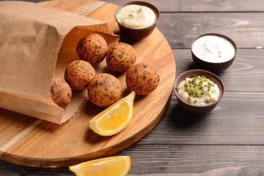 Ahşap masa üzerinde lezzetli falafel topları ve sos ile Kurulu